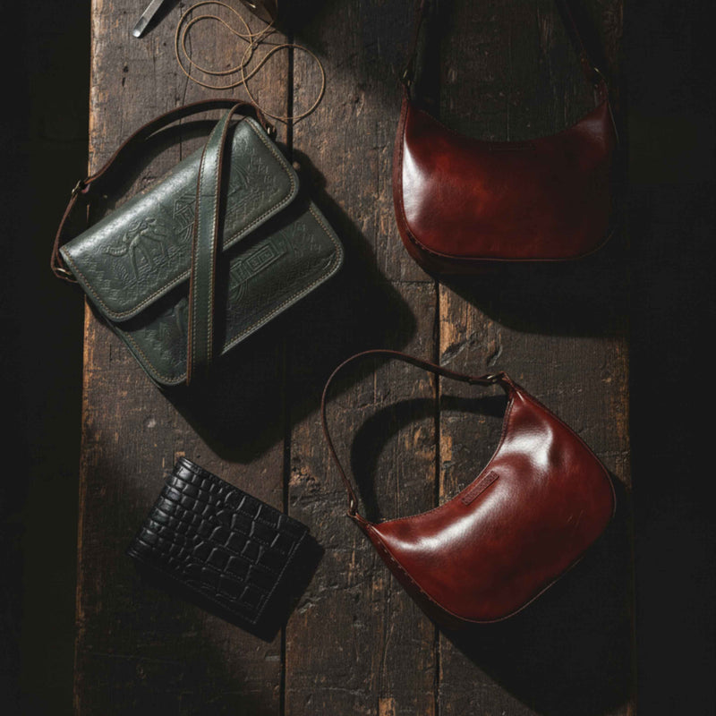 A curated collection of Jeengar's bestselling handcrafted leather bags and wallets, presented by an artisan on a textural fabric background.