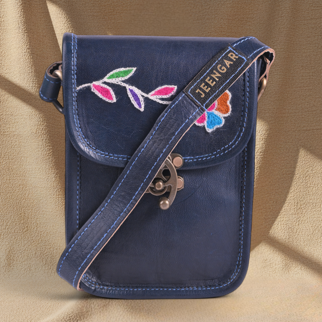 Blue crossbody bag with floral embroidery on a beige background