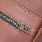 Close-up of a brown leather laptop bag with a zipper