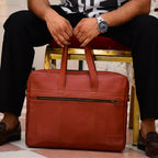 Person holding a brown leather briefcase with a gold chair and patterned floor in the background
