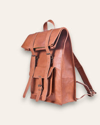 The Sariska Backpack, a tall 20-inch handcrafted tan goat leather fold-over rucksack with dual vertical straps by Jeengar.