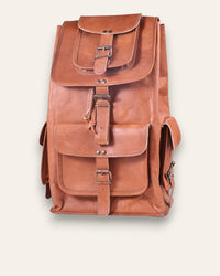 The Aravalli Backpack, a handcrafted tan goat leather rucksack featuring a buckled top flap and three exterior pockets by Jeengar.