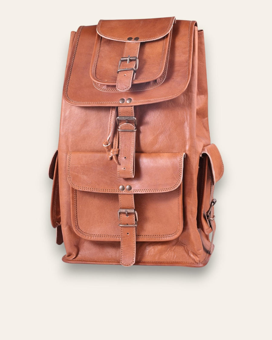 The Aravalli Backpack, a handcrafted tan goat leather rucksack featuring a buckled top flap and three exterior pockets by Jeengar.