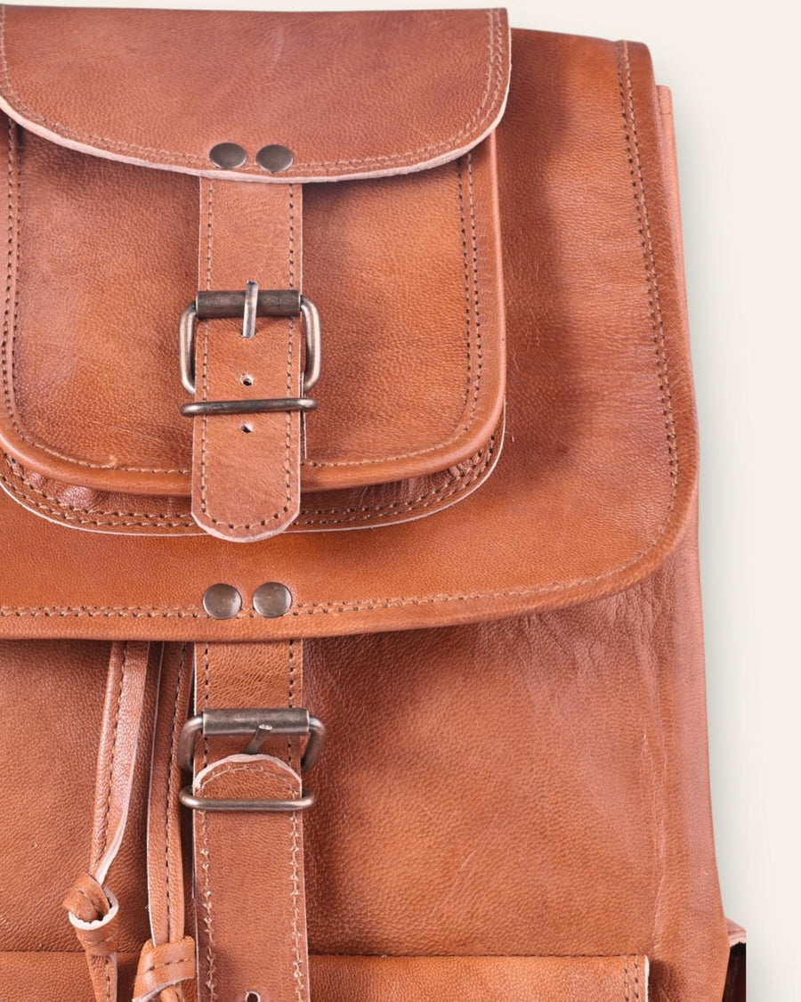 The Aravalli Backpack, a handcrafted tan goat leather rucksack featuring a buckled top flap and three exterior pockets by Jeengar.