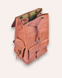 The Aravalli Backpack, a handcrafted tan goat leather rucksack featuring a buckled top flap and three exterior pockets by Jeengar.