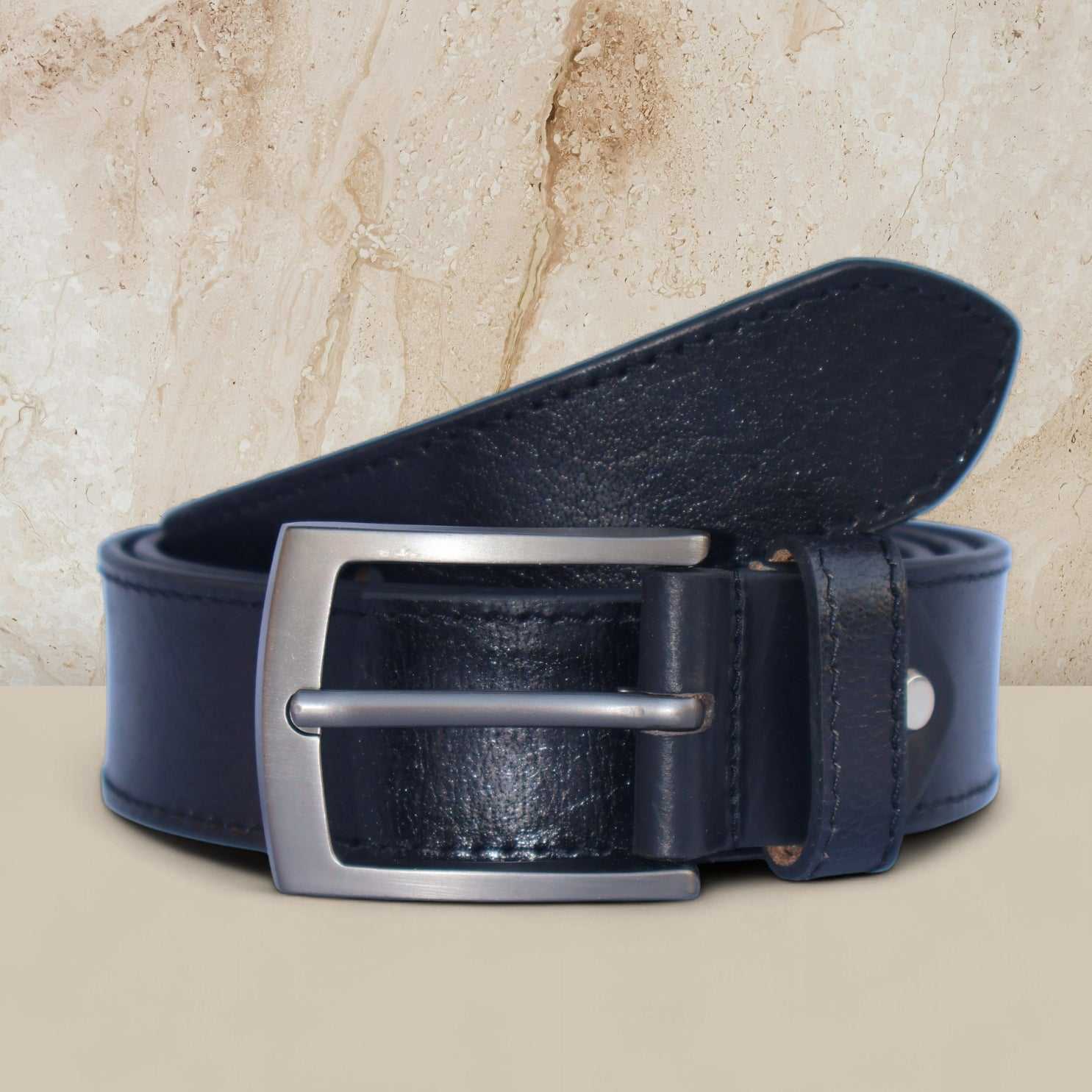 Black leather belt with a silver buckle on a beige background