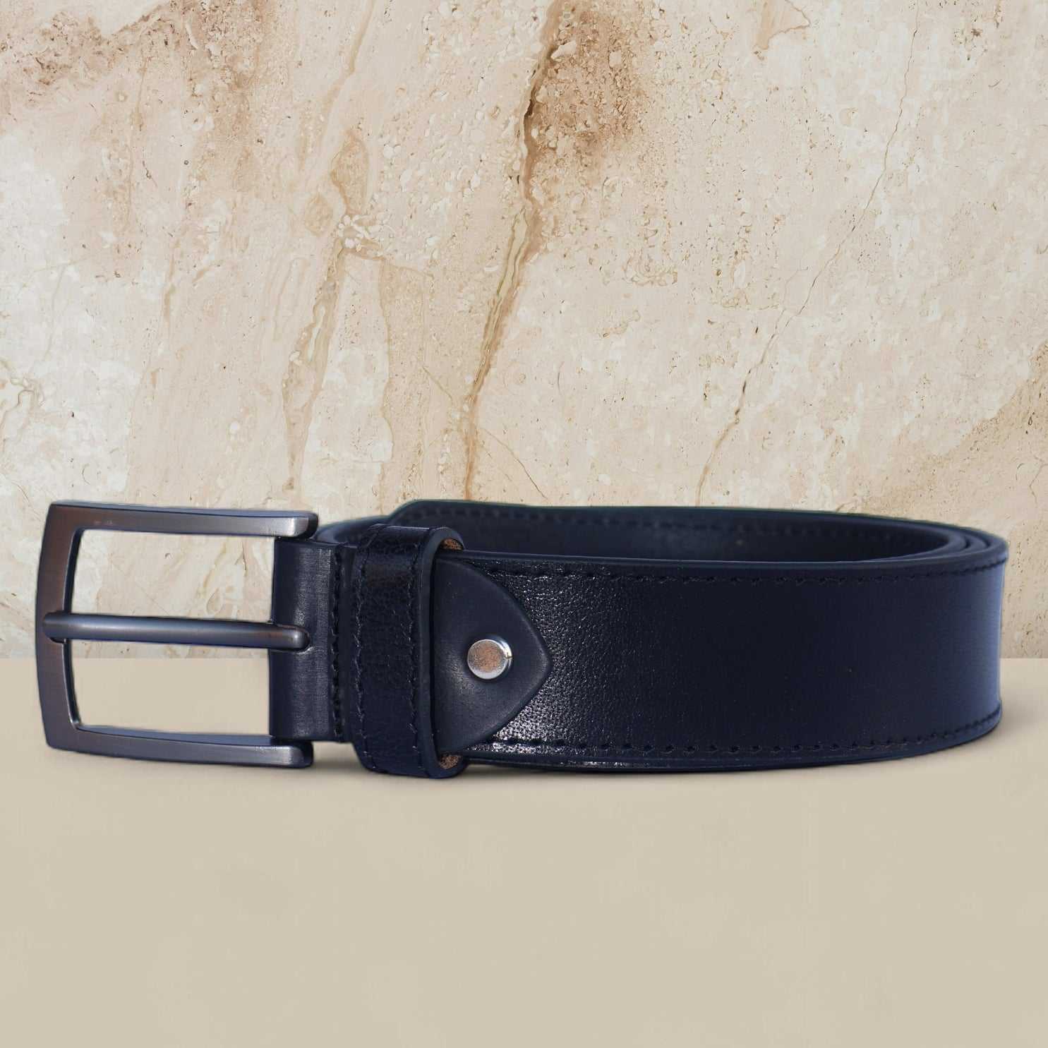 Black leather belt with a silver buckle on a beige background