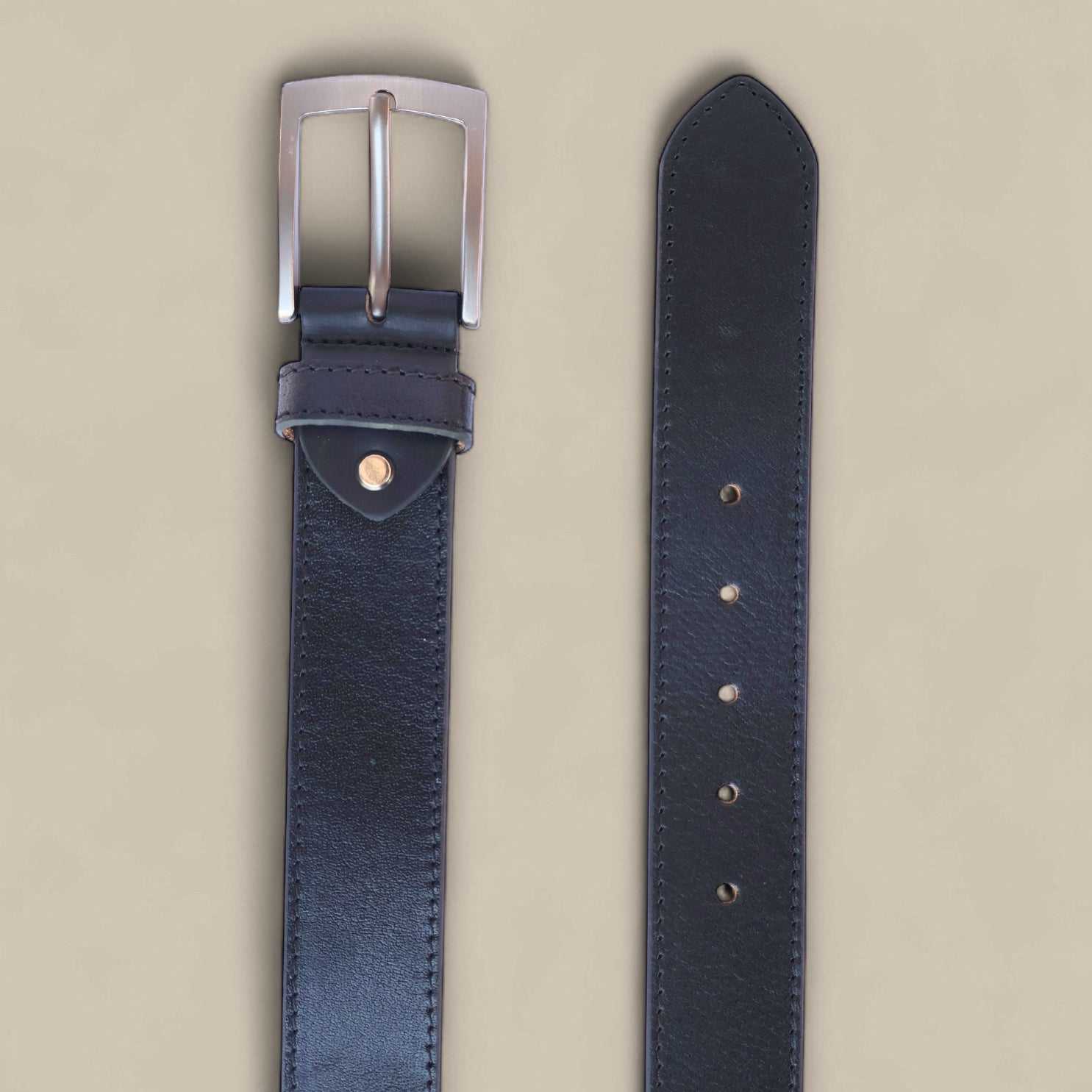 Black leather belt with silver buckle on a beige background