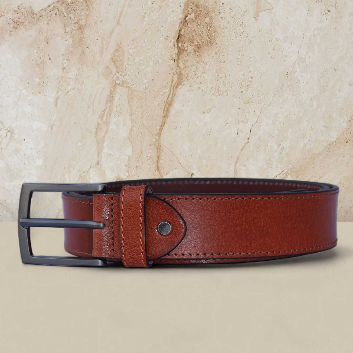 Brown leather belt with black buckle on a beige marble background