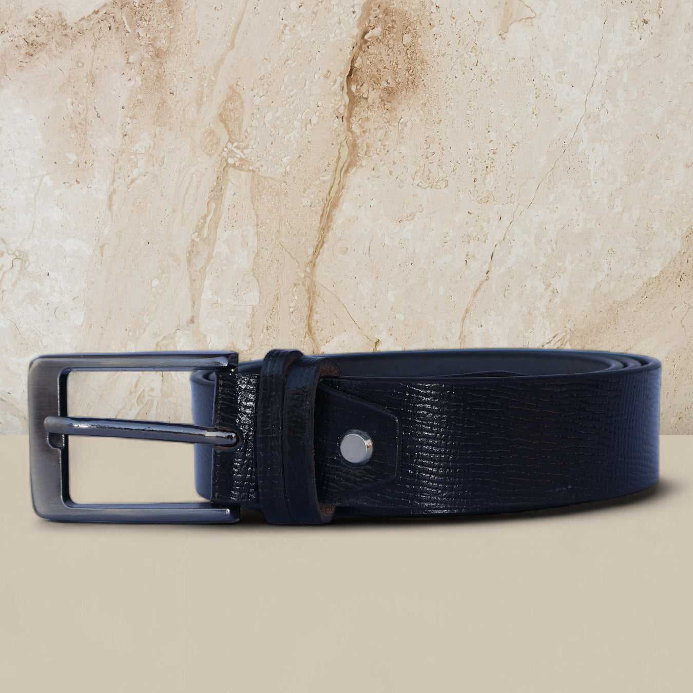 Black blue leather belt with a silver buckle on a beige marble background