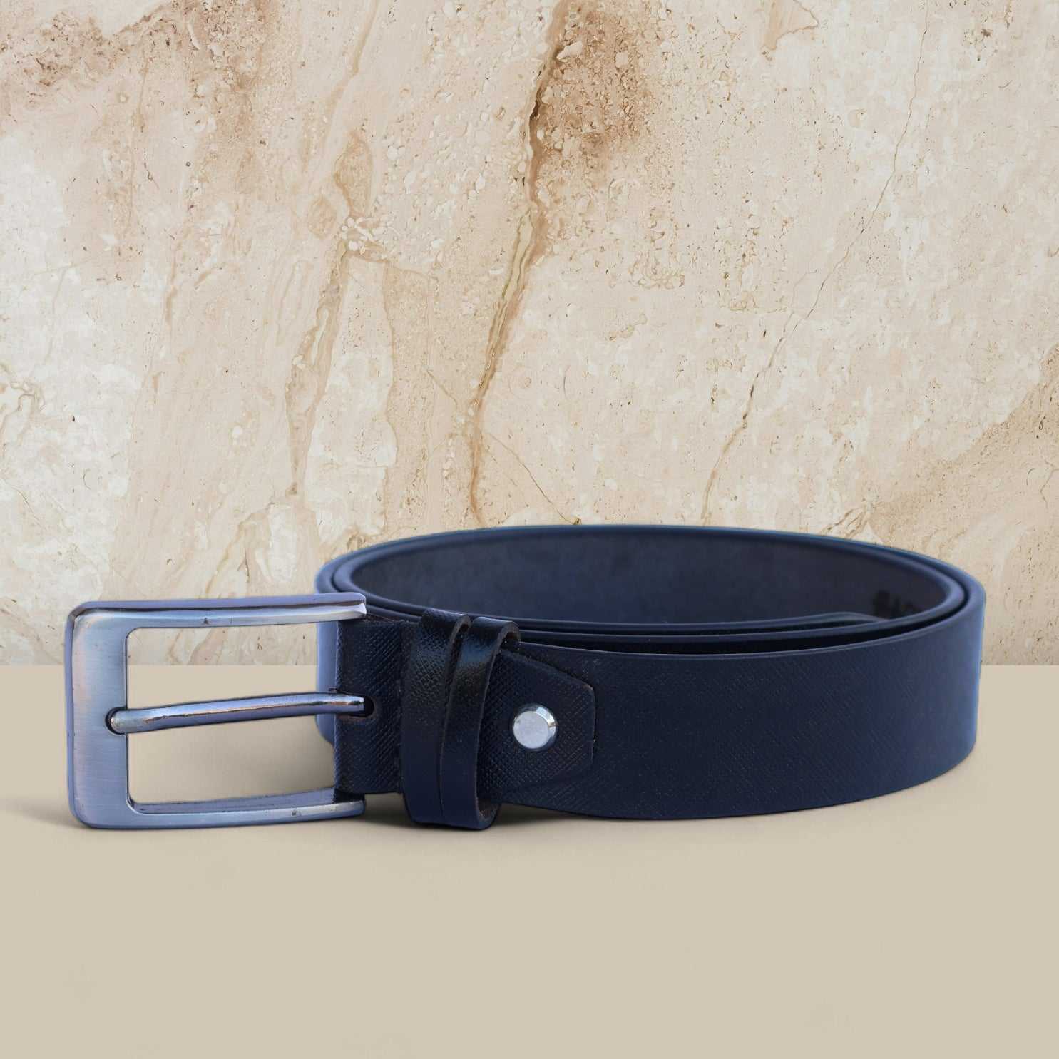 Black belt with silver buckle on a beige marble background
