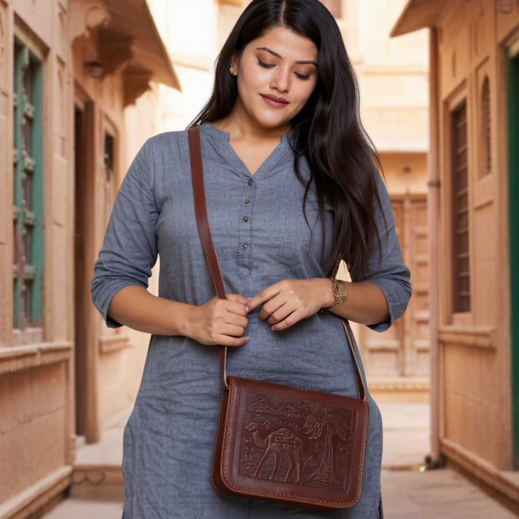 Woman wearing a blue dress with a cherry red embroidered leather bag in an outdoor setting