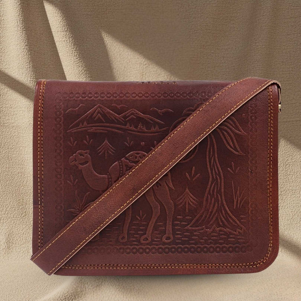A cherry red leather bag with embossed design of a camel and mountains on a beige background
