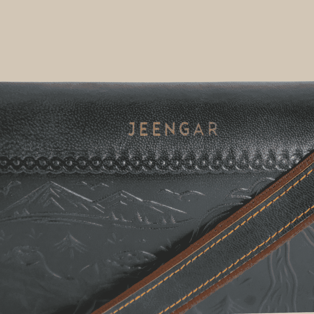 Close-up of a dark green leather bag with 'JEENGAR' branding and mountain embossing.