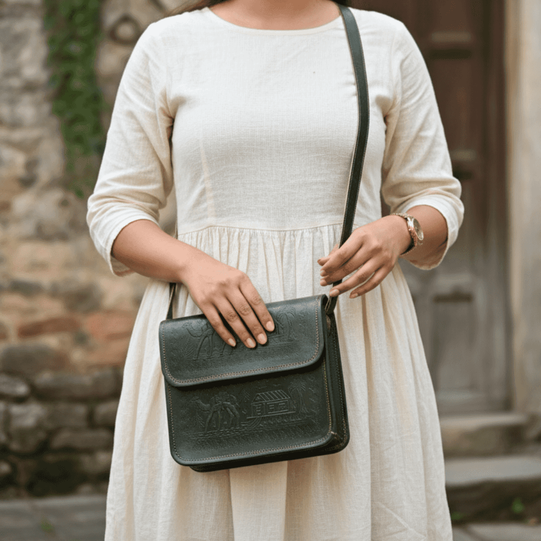 Person holding a dark olive leather handbag with a stone wall background