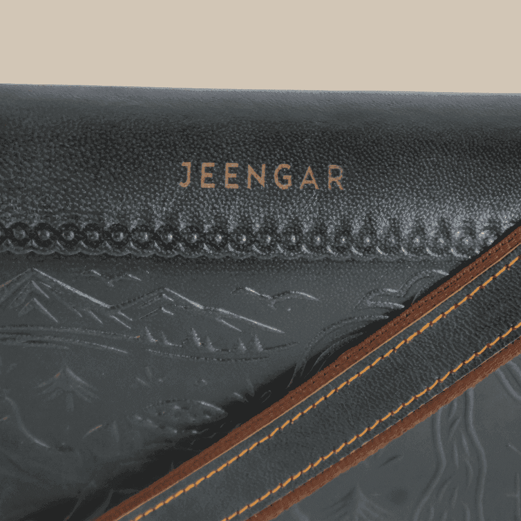 Close-up of a dark green leather product with 'JEENGAR' branding and mountain embossing.