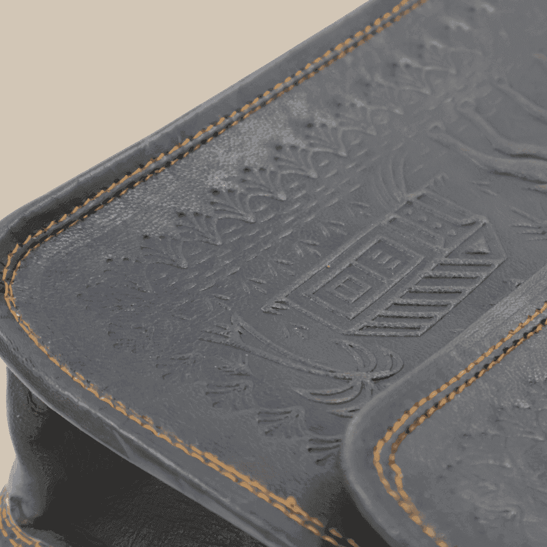 Close-up of a embossed leather bag surface with intricate patterns and stitching details.