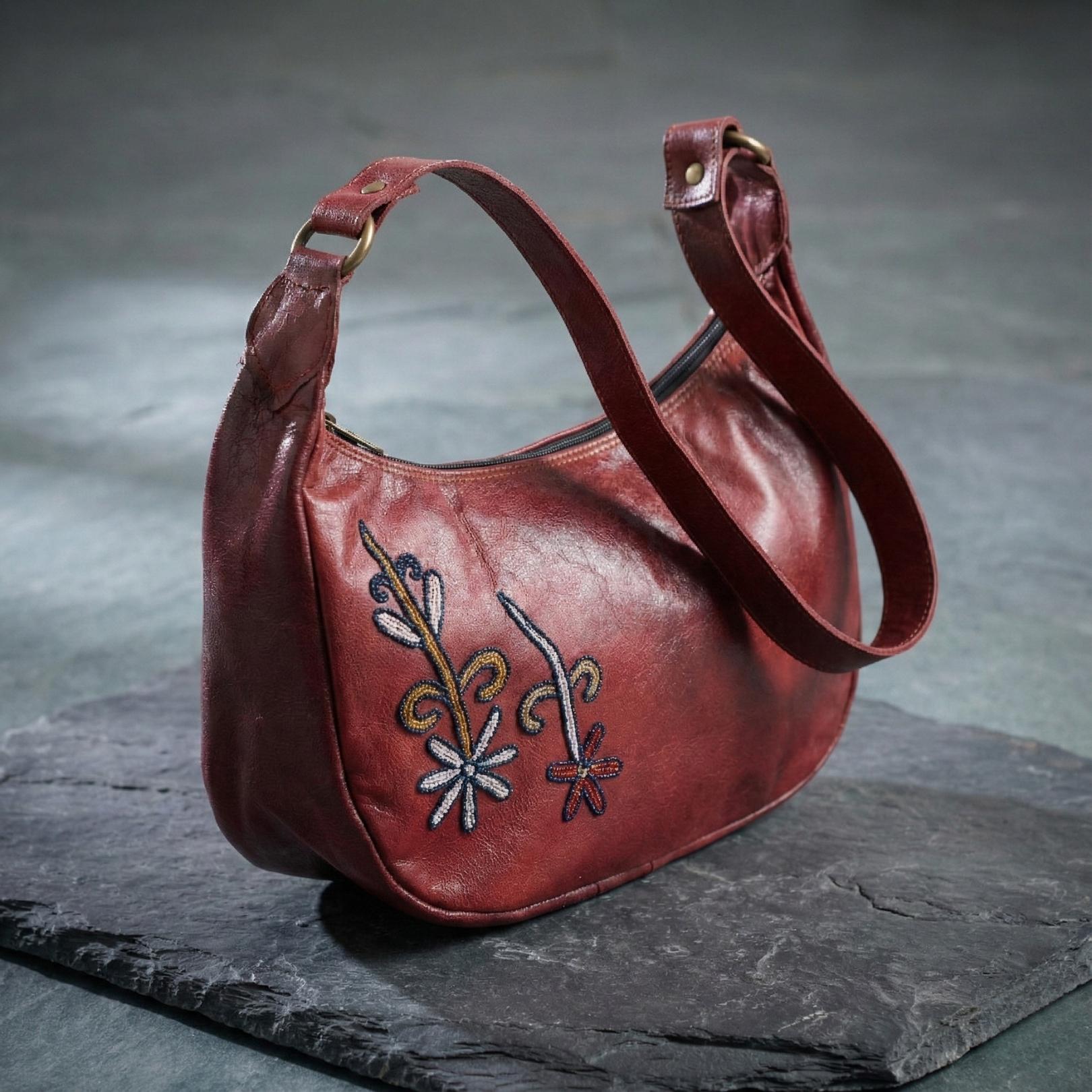 The Mira Shoulder Bag in cherry top-grain leather, with hand-embroidered Rajasthani folk-art motifs.