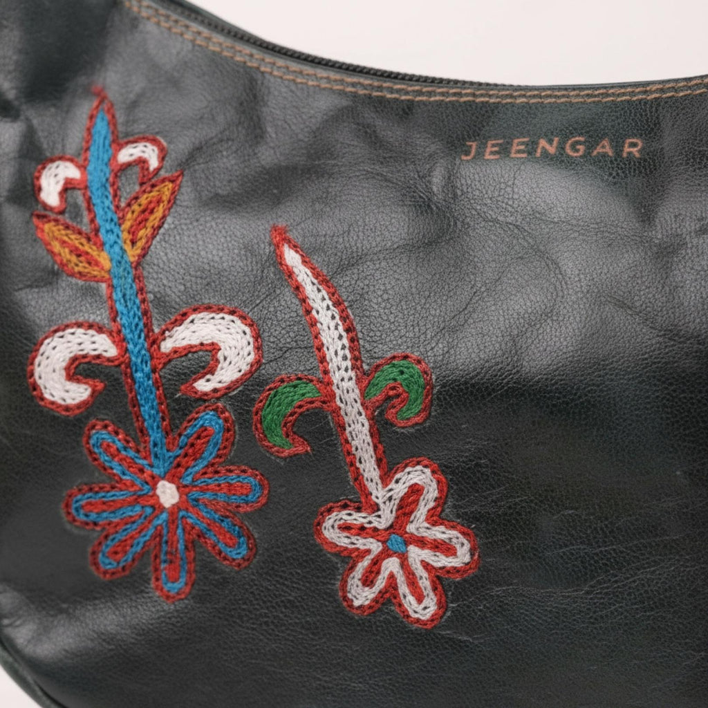Close-up of the unique folk-art embroidery on the Mira leather shoulder bag.