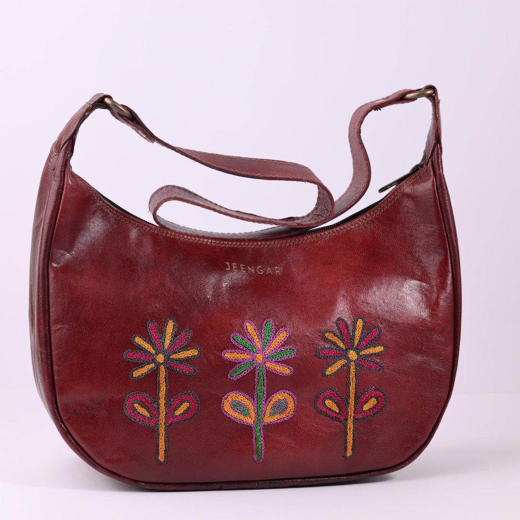 The Sanyogita Shoulder Bag in cherry top-grain leather, featuring colorful floral embroidery.