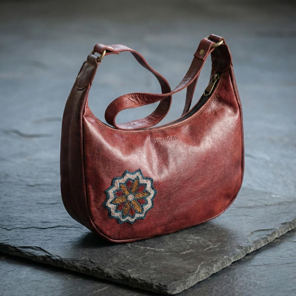 The Hadi Shoulder Bag in cherry top-grain leather, featuring a colorful embroidered medallion.