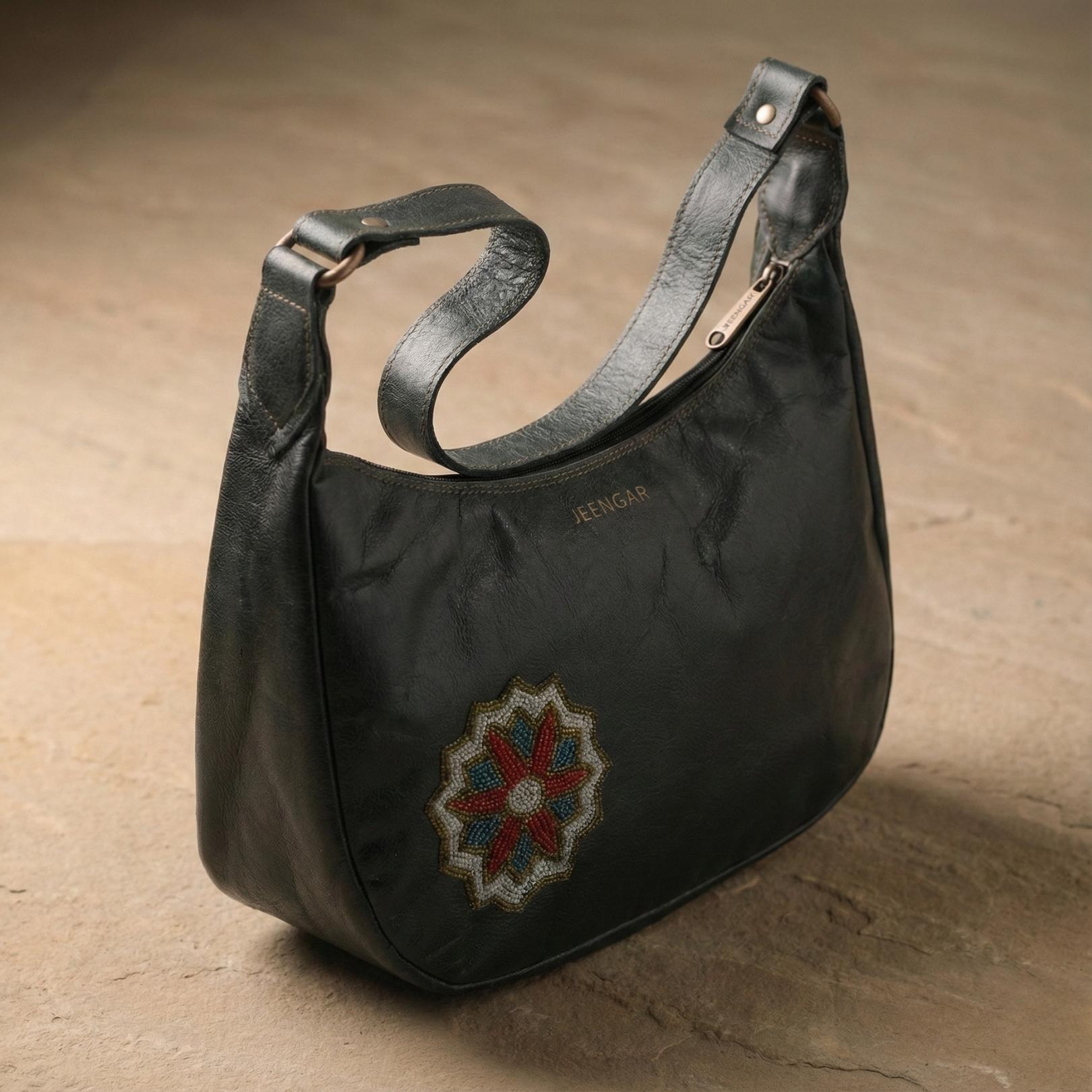The Hadi Shoulder Bag in dark olive top-grain leather, with a hand-embroidered geometric medallion.