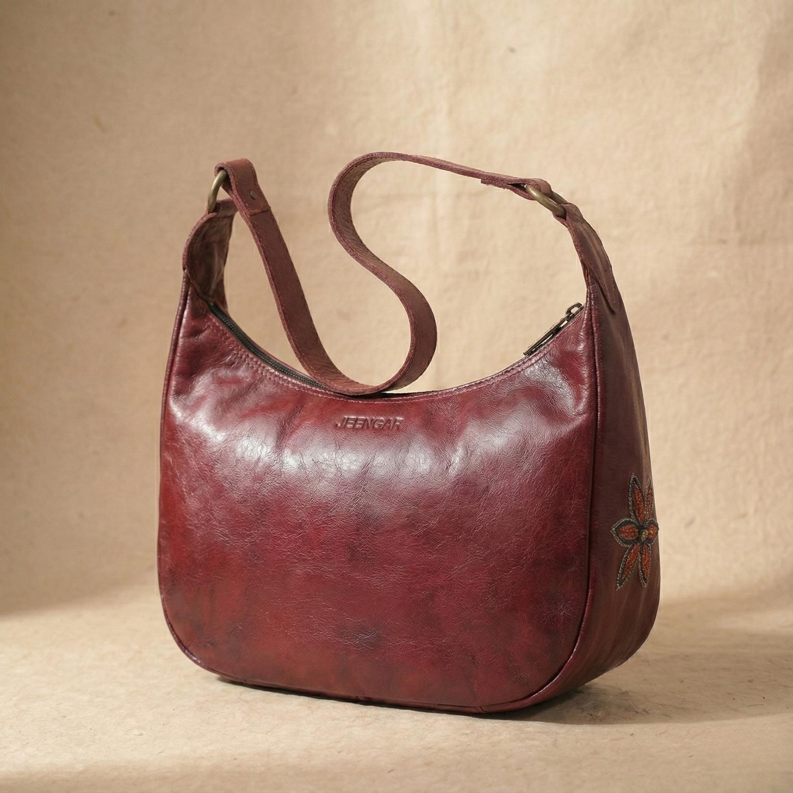 The Moomal Shoulder Bag in cherry top-grain leather, with a single, asymmetrically placed hand-embroidered flower.