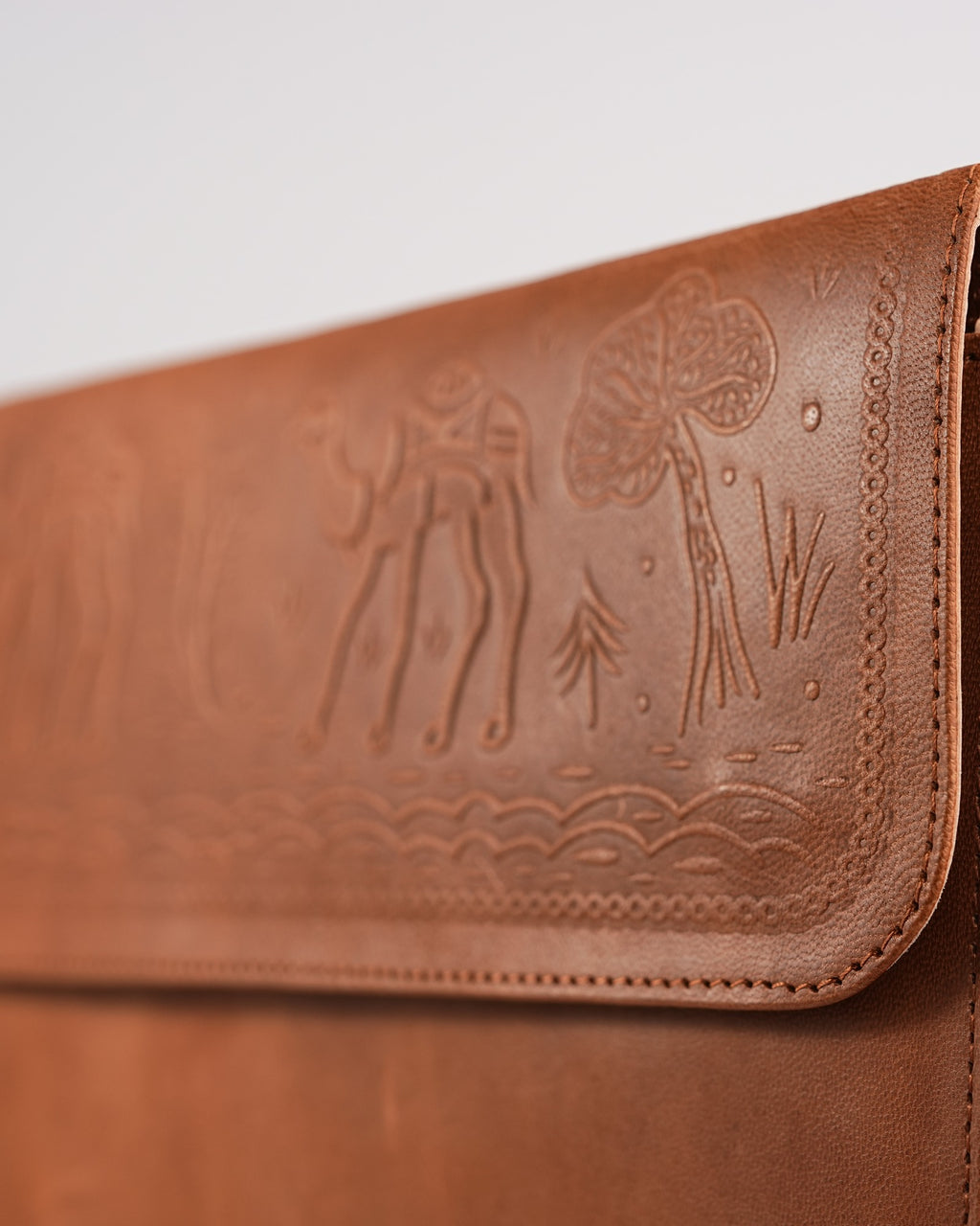 The Barmer Tech Sleeve — close-up of the hand-embossed camel caravan motif