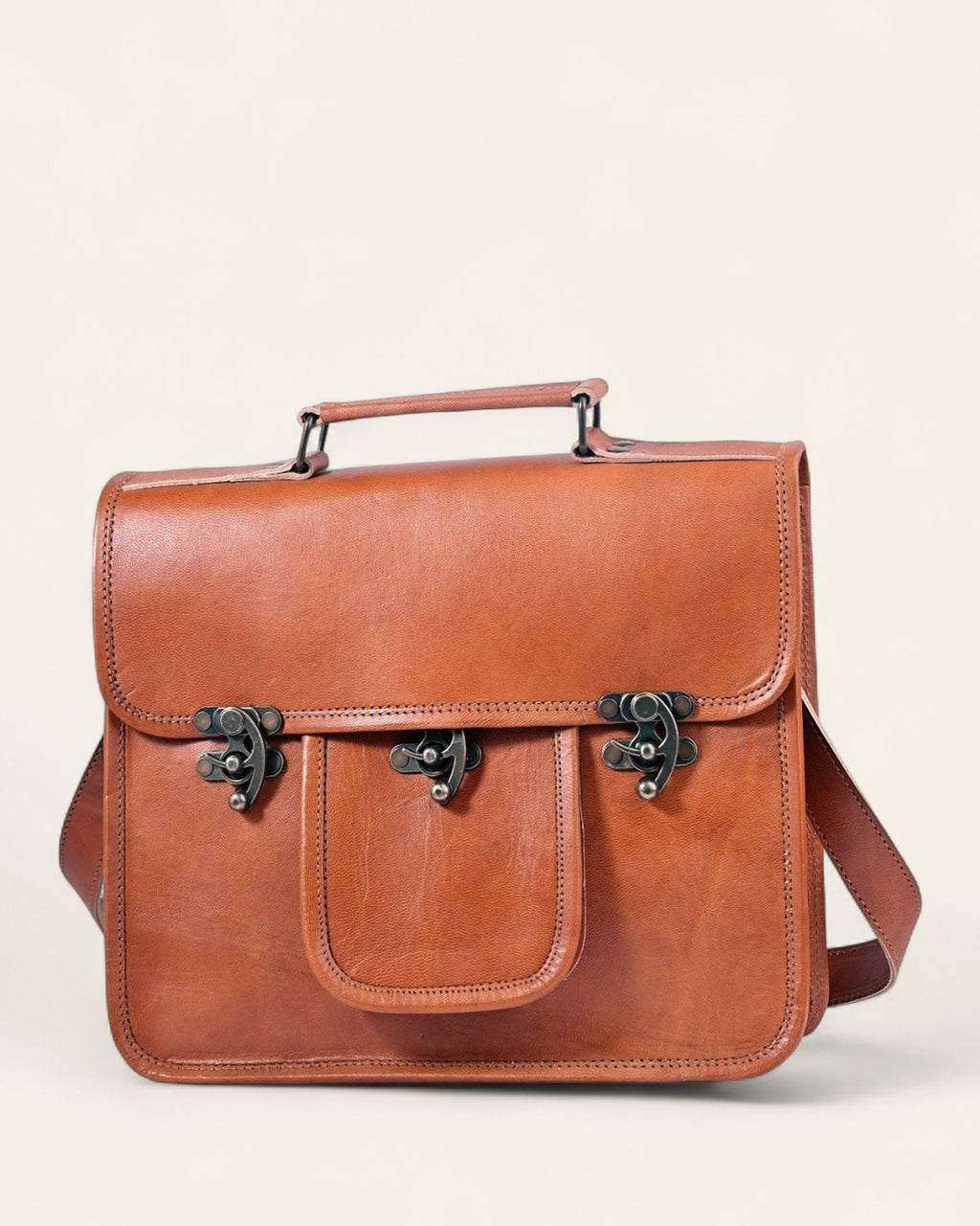 The Neemrana Twist-Lock Messenger in natural-brown certified real leather — front view with twist-lock pocket and top handle