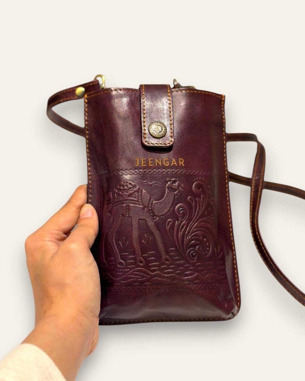The Osian Mobile Sling in Cherry — hand-embossed camel motif on real leather, front view