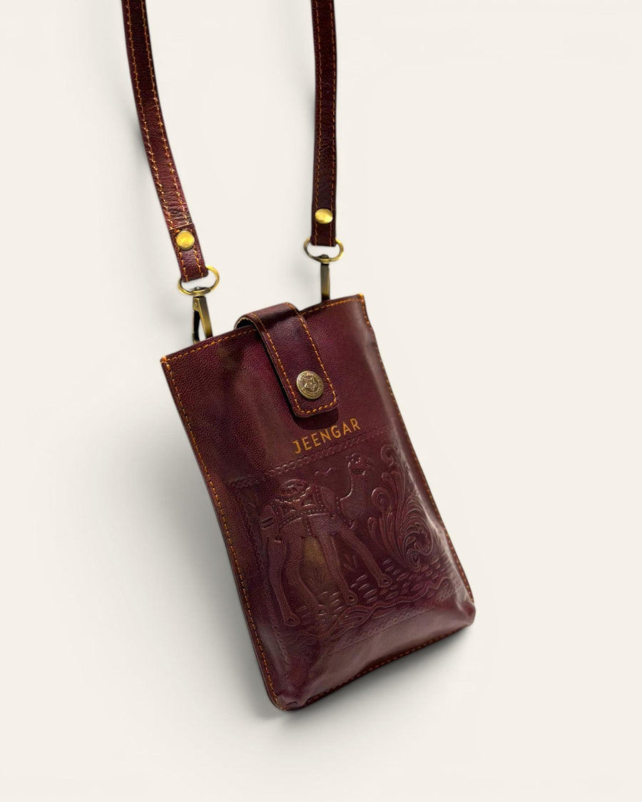 The Osian Mobile Sling, a handcrafted cherry red leather phone bag featuring a hand-embossed camel motif by Jeengar.