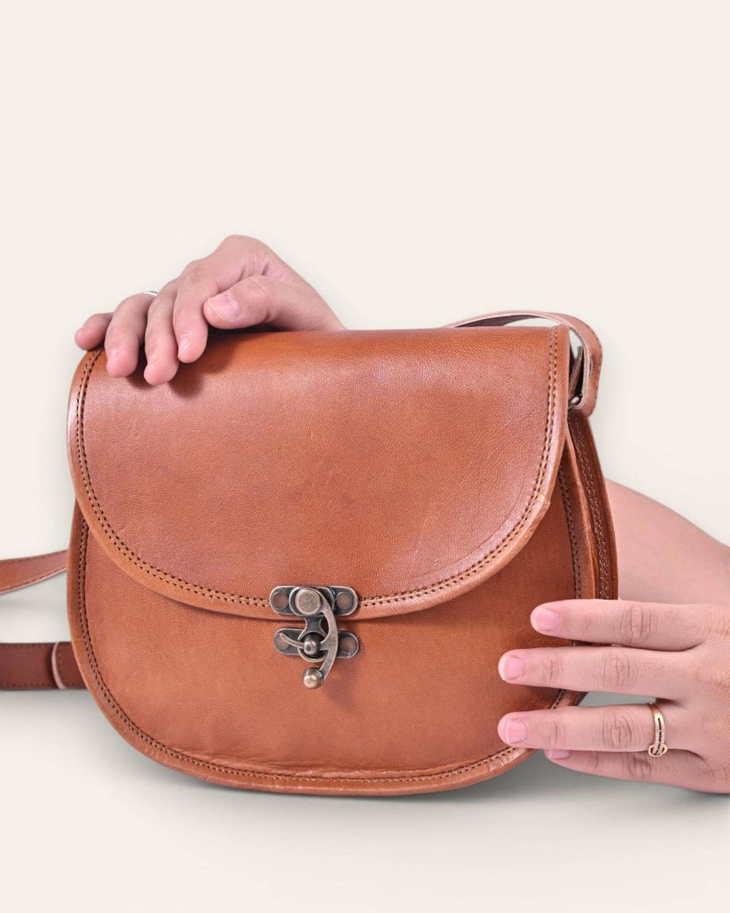 The Udaipur Saddle Bag — graceful curved silhouette in tan leather