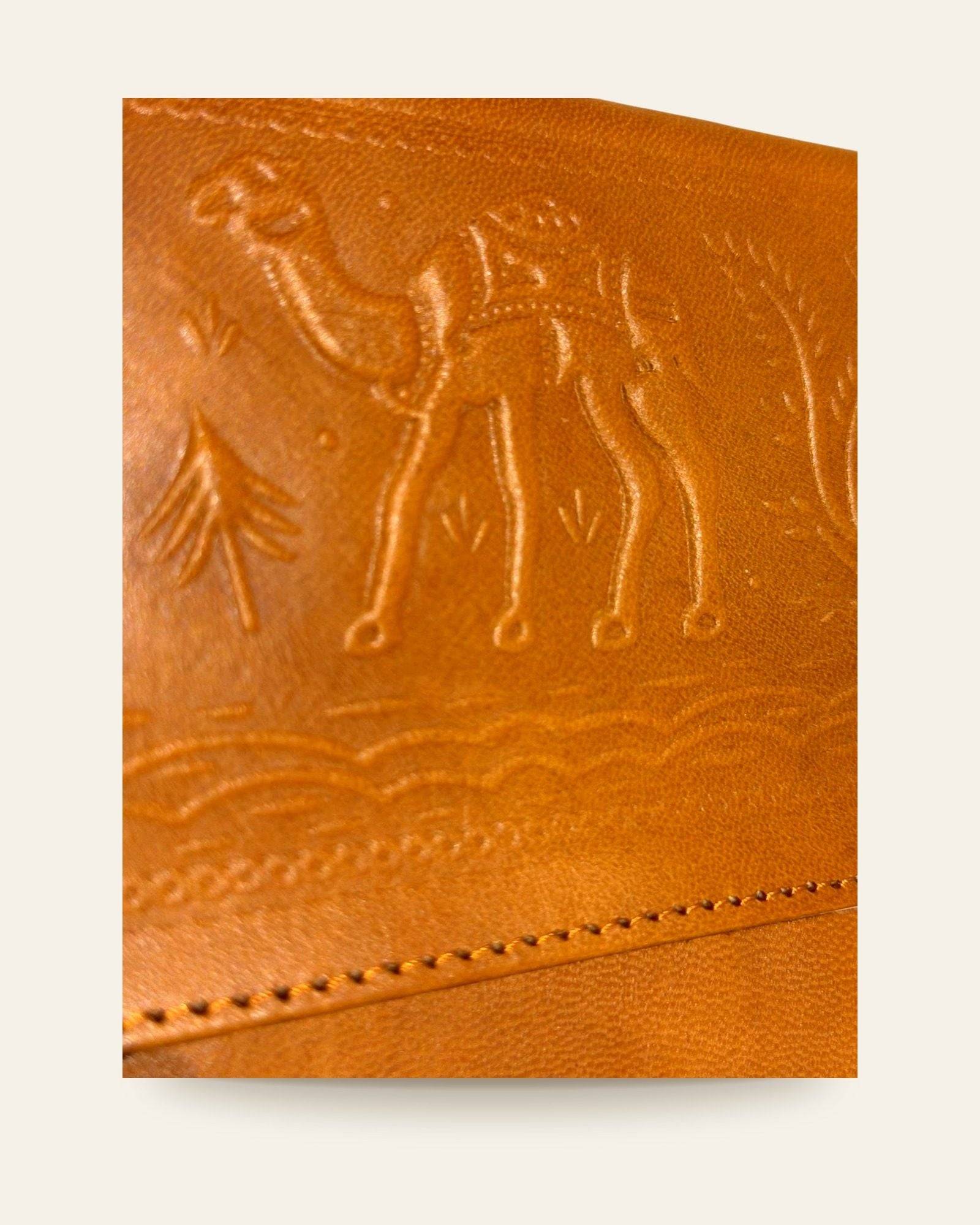 The Barmer Tech Sleeve — close-up of the hand-embossed camel caravan motif