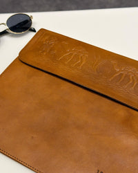 The Barmer Tech Sleeve, a handcrafted tan full-grain leather iPad and MacBook sleeve featuring a hand-embossed desert camel motif by Jeengar.