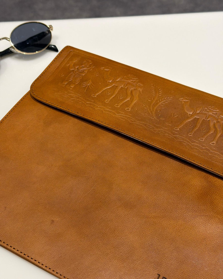 The Barmer Tech Sleeve, a handcrafted tan full-grain leather iPad and MacBook sleeve featuring a hand-embossed desert camel motif by Jeengar.