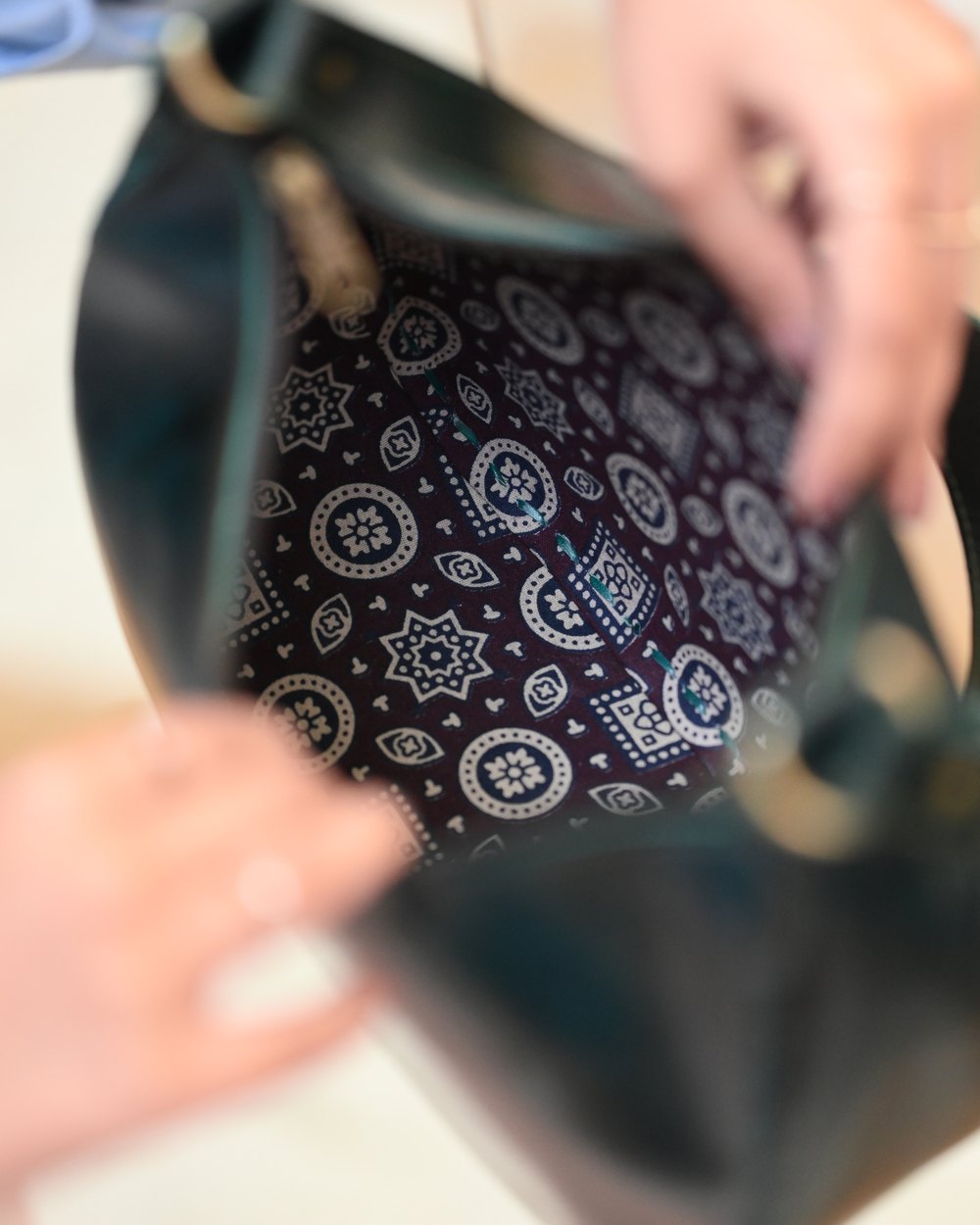 Two hands holding a Jeengar bag open, showing the block-printed lining inside.